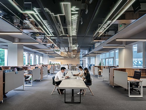 Three people working at a communal table in an office.