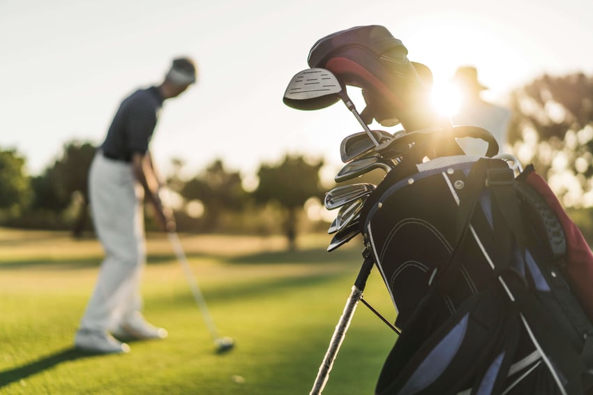 692758219 A photo of senior man and woman at golf course. Focus is on golf bag. They are playing on sunny day.