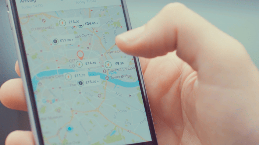 Mão segurando um celular com o aplicativo JustPark aberto mostrando mapa