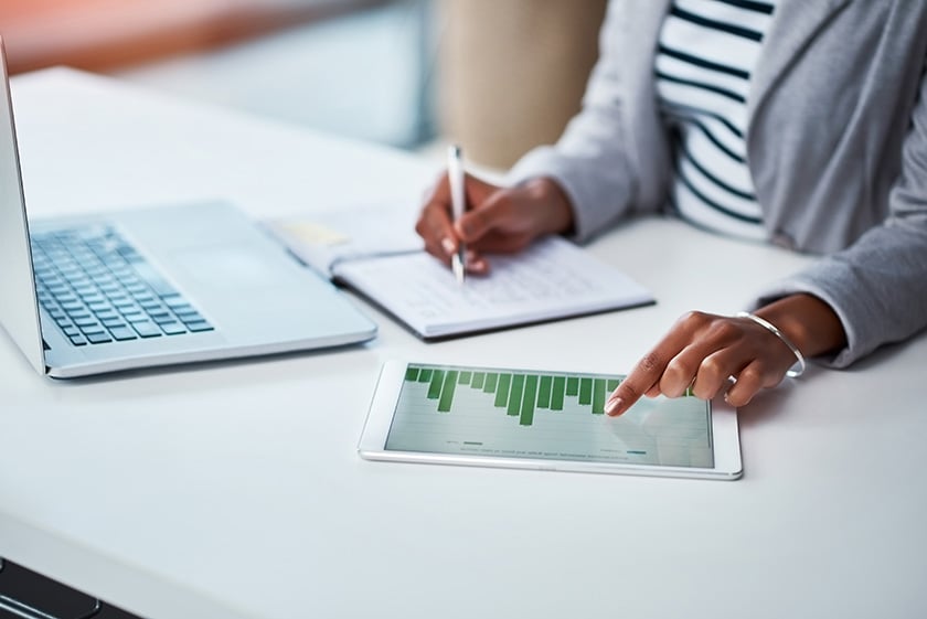 1041512864 Pessoa anotando informações financeiras de gráfico com laptop em frente
