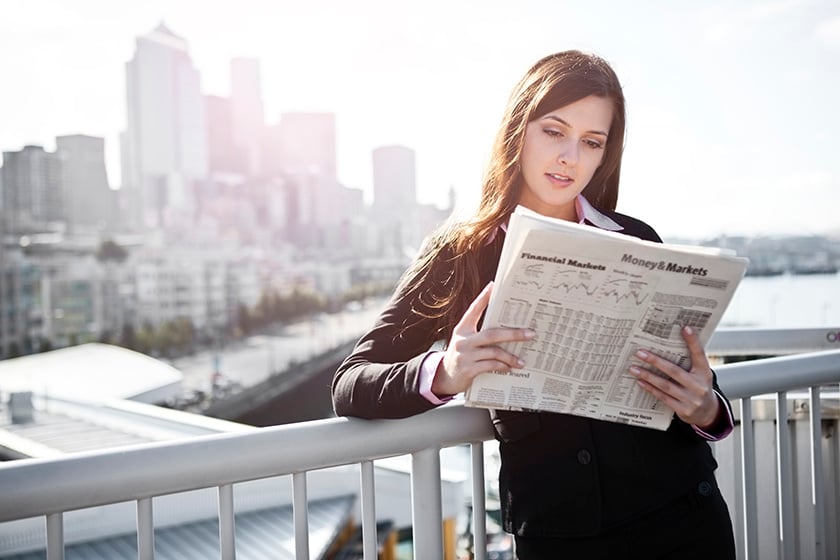 Mulher encostada na cerca lendo jornal