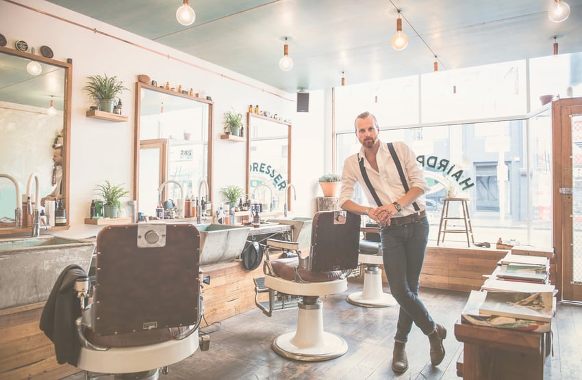 Estilista caucasiano sorrindo na barbearia